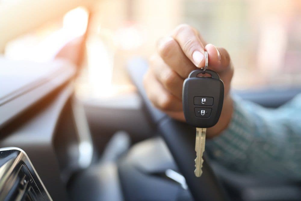A hand holding a car key with a remote fob